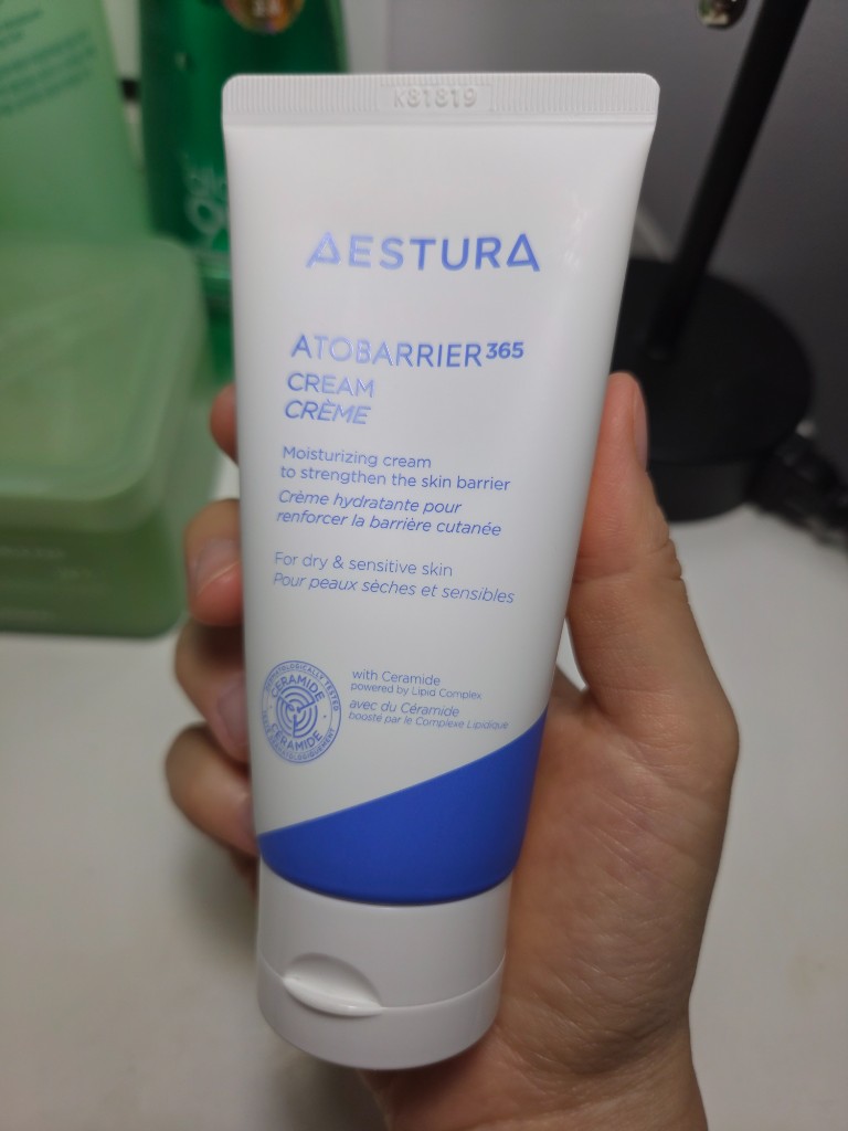 Front of an AESTURA ATOBARRIER365 Cream tube held in hand, showing the blue and white packaging