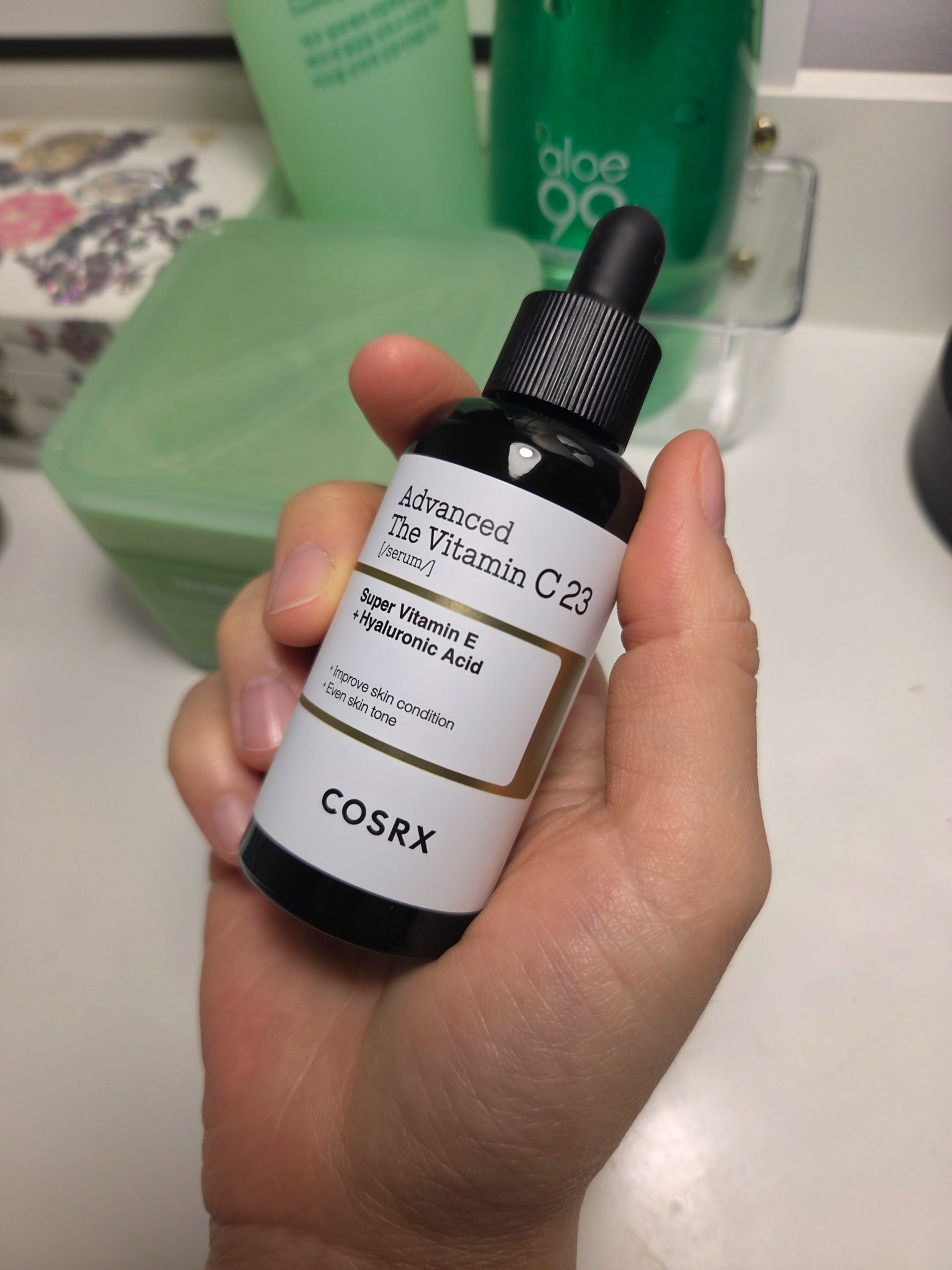 Front of a COSRX The Vitamin C 23 Serum bottle held in hand, showing the orange dropper and Advanced Vitamin C 23 label
