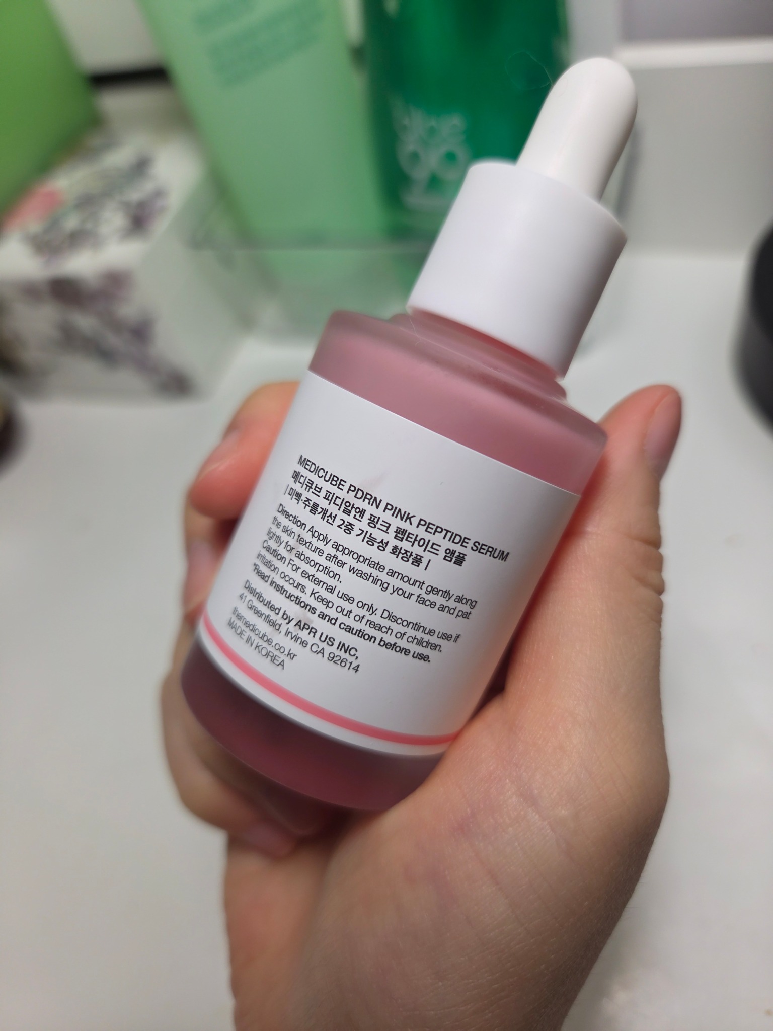 Back label of the Medicube PDRN Pink Peptide Serum bottle held in Kay’s hand