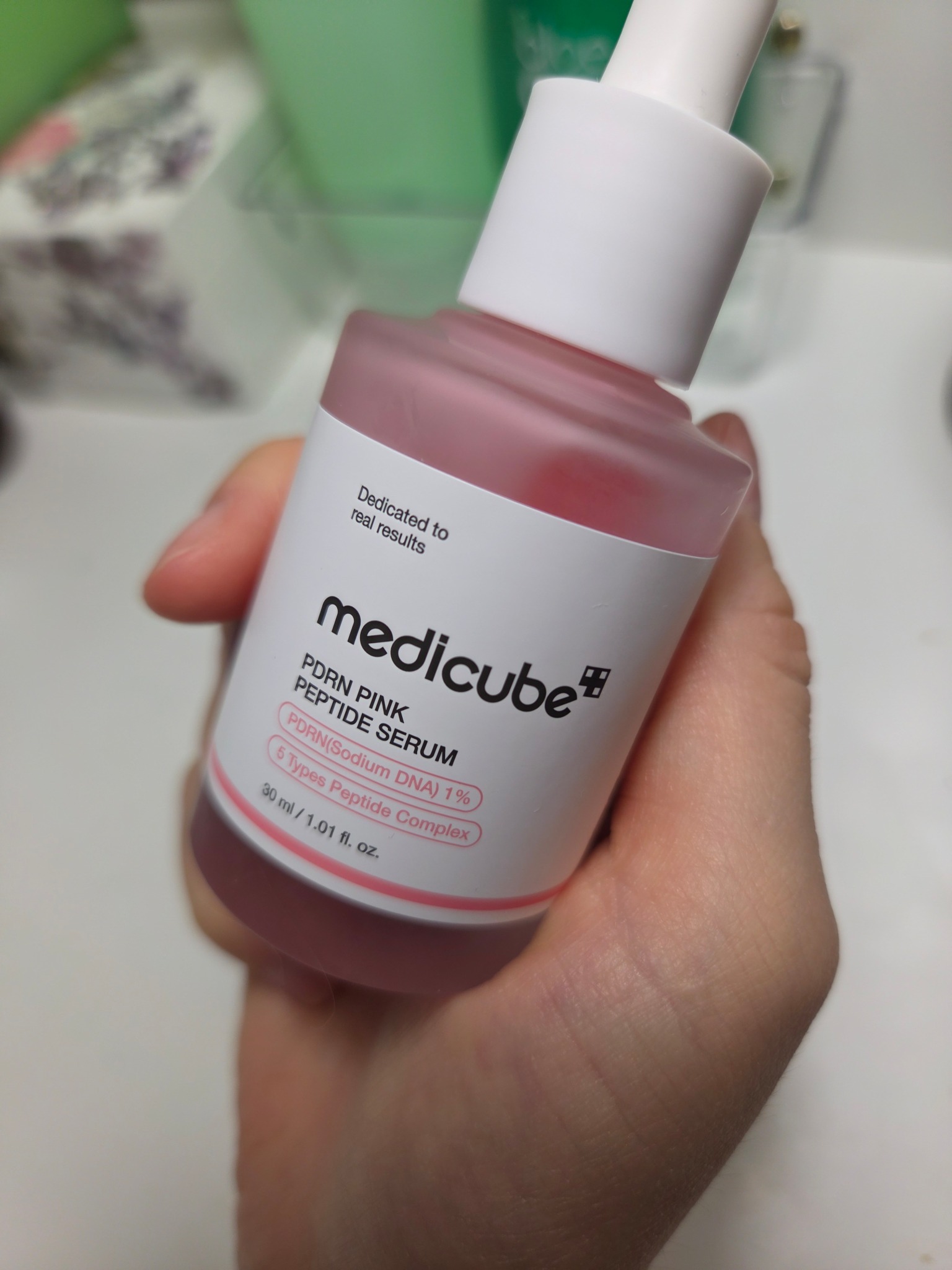 Front of the Medicube PDRN Pink Peptide Serum bottle held in Kay’s hand